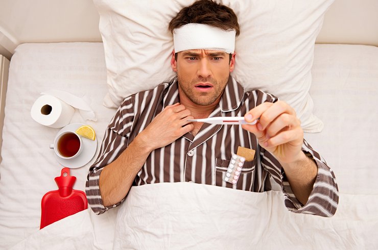 Мужчина на кровати и вокруг него всевозможные лекарства
